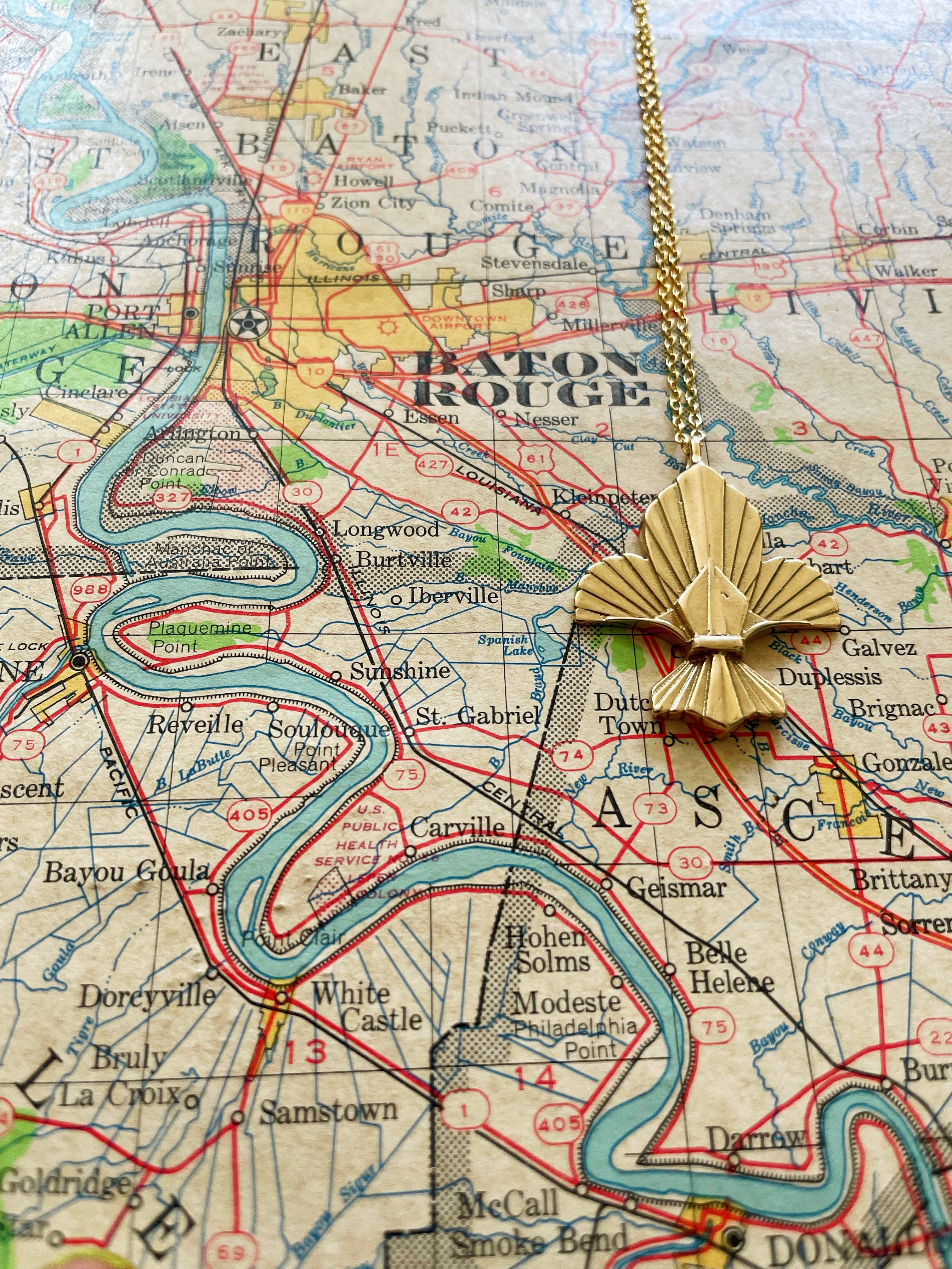 MIMOSA Handcrafted's Fleur De Lis Pendant Is Displayed With A Map of Baton Rouge