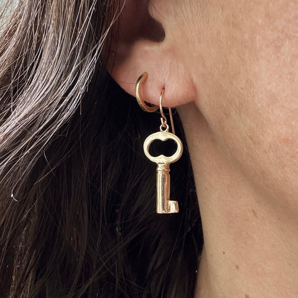 Woman Wears the MIMOSA Handcrafted Key Earrings in Bronze