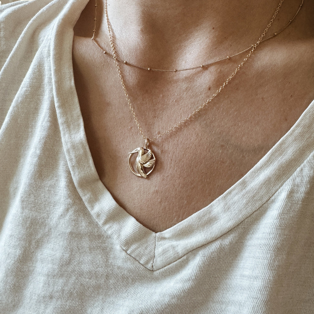 Woman Wears the MIMOSA Handcrafted Hummingbird Pendant in Bronze