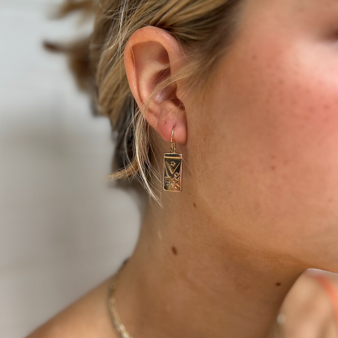 Woman Wears MIMOSA Handcrafted Acadian Flag Earrings in Bronze.