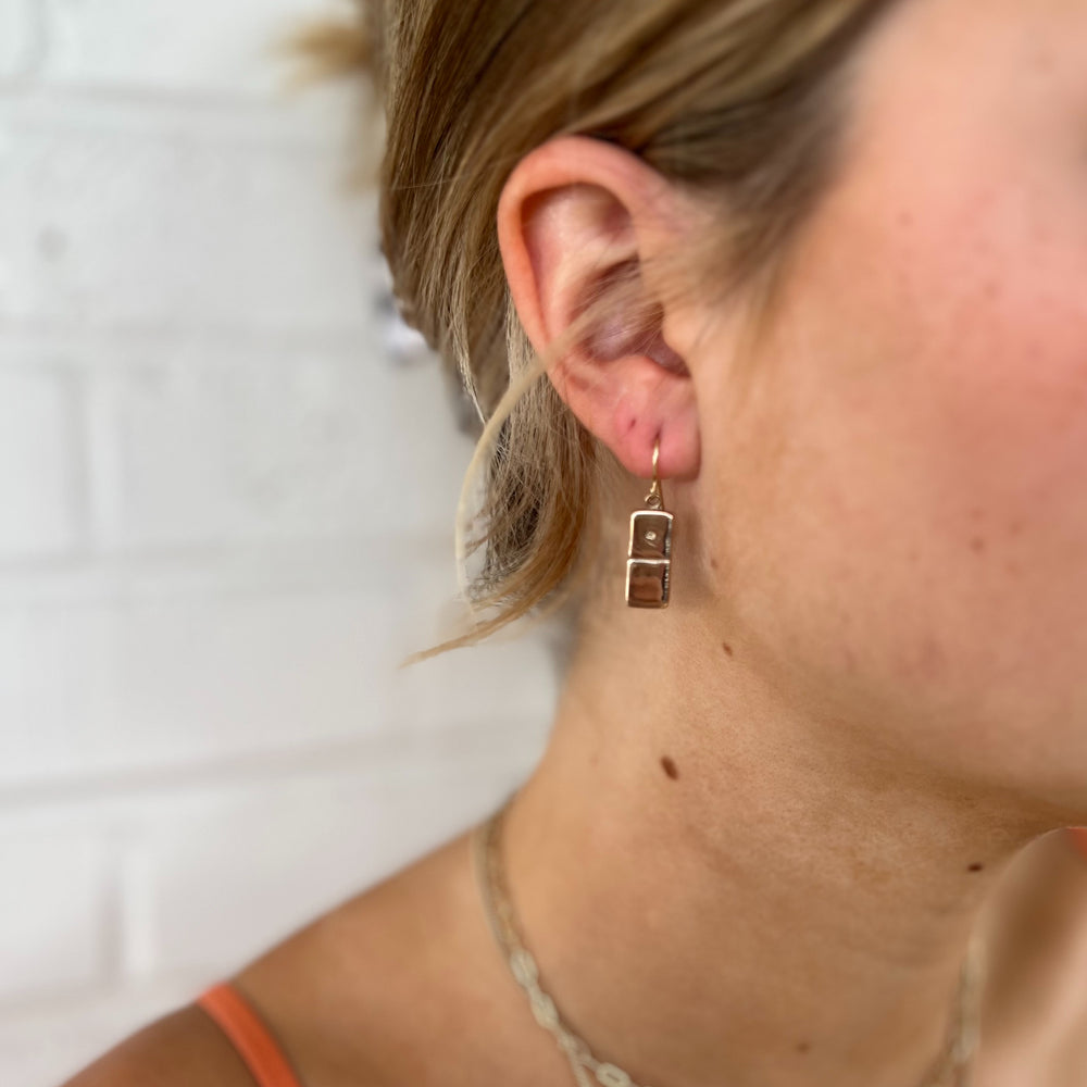 Woman Wears MIMOSA Handcrafted Domino Earrings in Bronze.