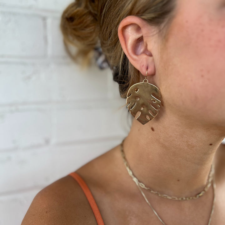 Woman Wears MIMOSA Handcrafted Monstera Earrings in Bronze.