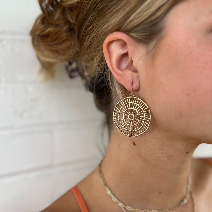 Woman Wears MIMOSA Handcrafted Shimmering Sun Earrings in Bronze.