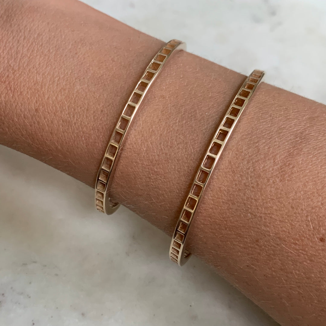 Woman Wearing Two Handmade Bronze Single Row Grid Cuff Bracelets