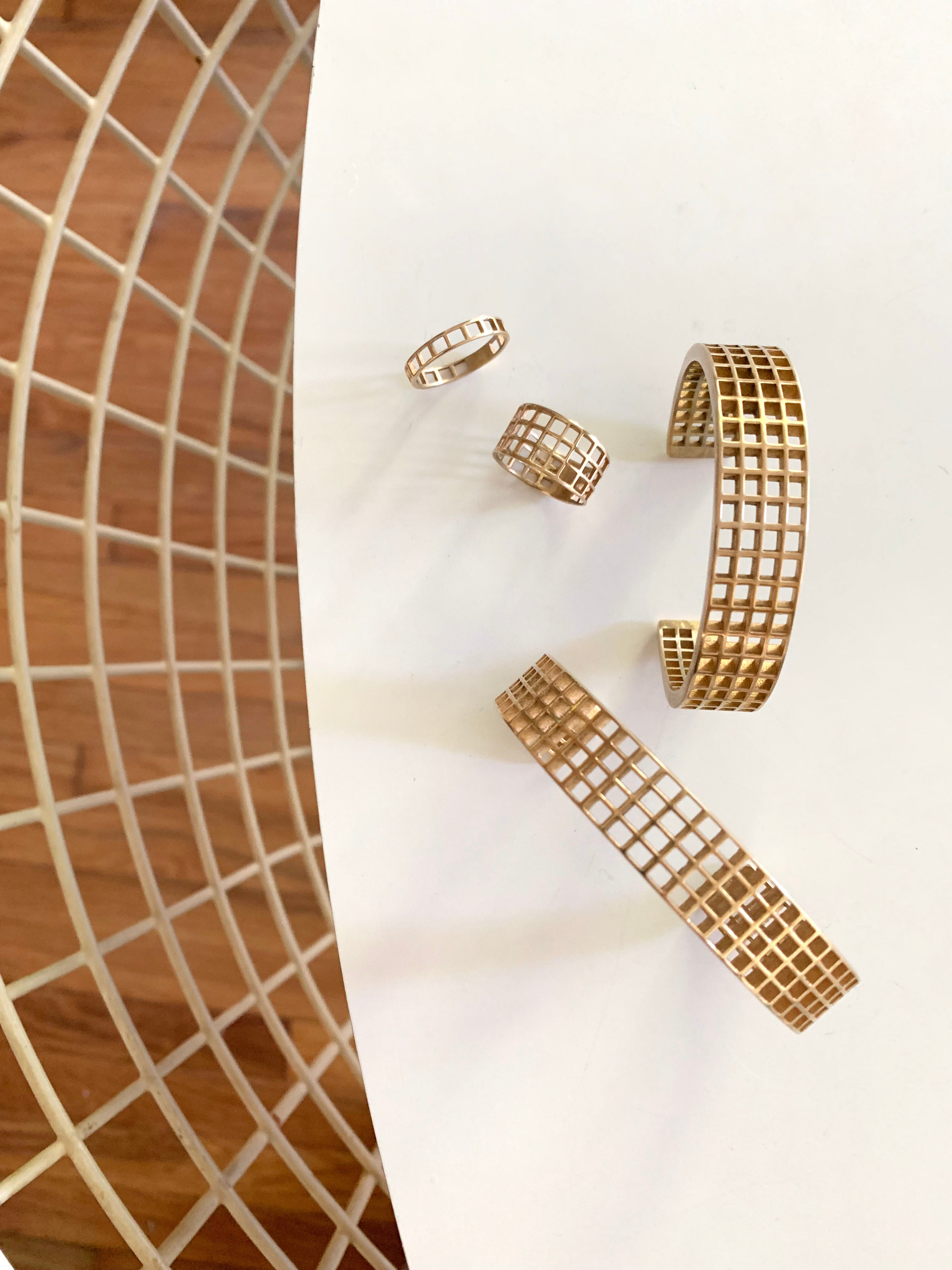 Mimosa Handcrafted's Bronze Grid Pattern Jewelry Is Displayed On A White Table