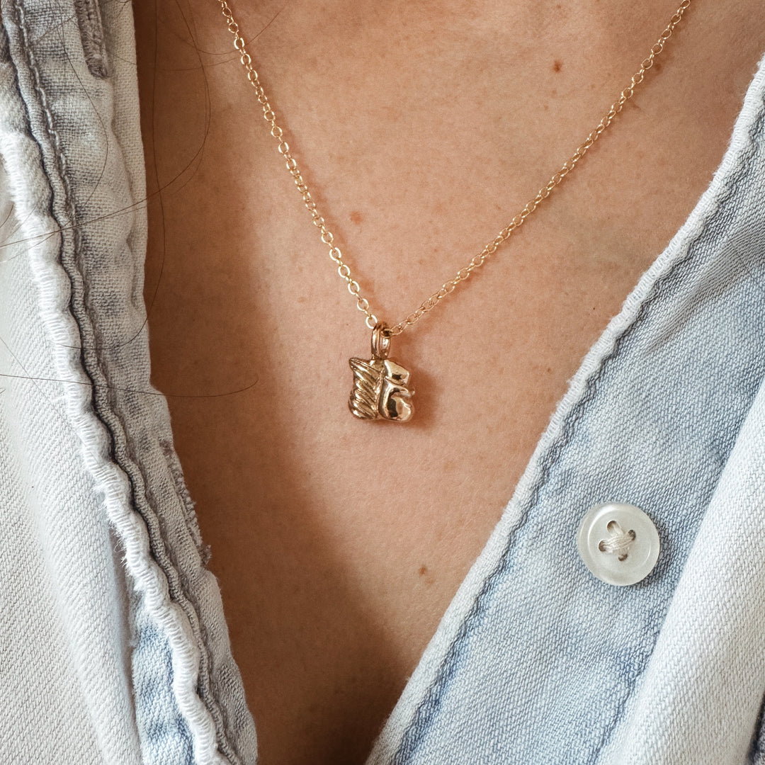 Woman Wears the MIMOSA Handcrafted Squirrel Necklace Charm in Bronze