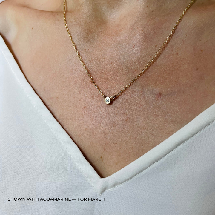 Handmade Bronze Birthstone Necklace with Aquamarine on Person Wearing a White Top