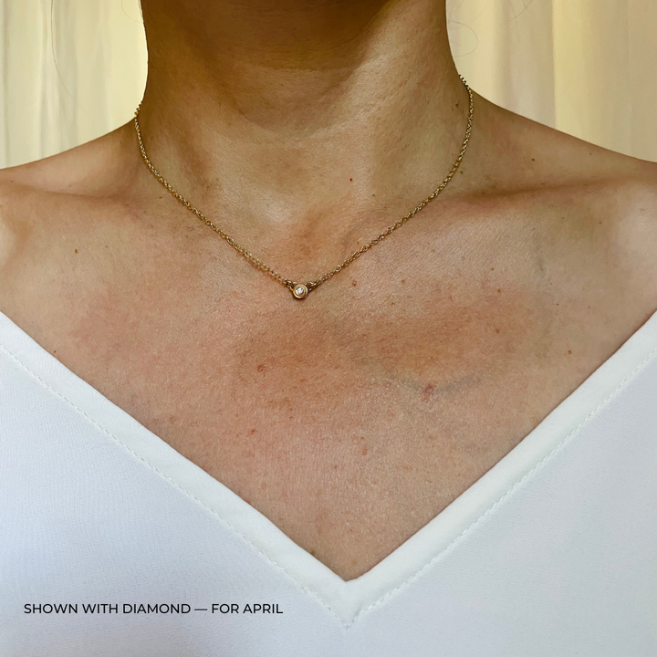 Handmade Bronze Birthstone Necklace with Diamond on Person Wearing a White Top