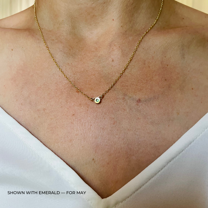 Handmade Bronze Birthstone Necklace with Emerald on Person Wearing a White Top
