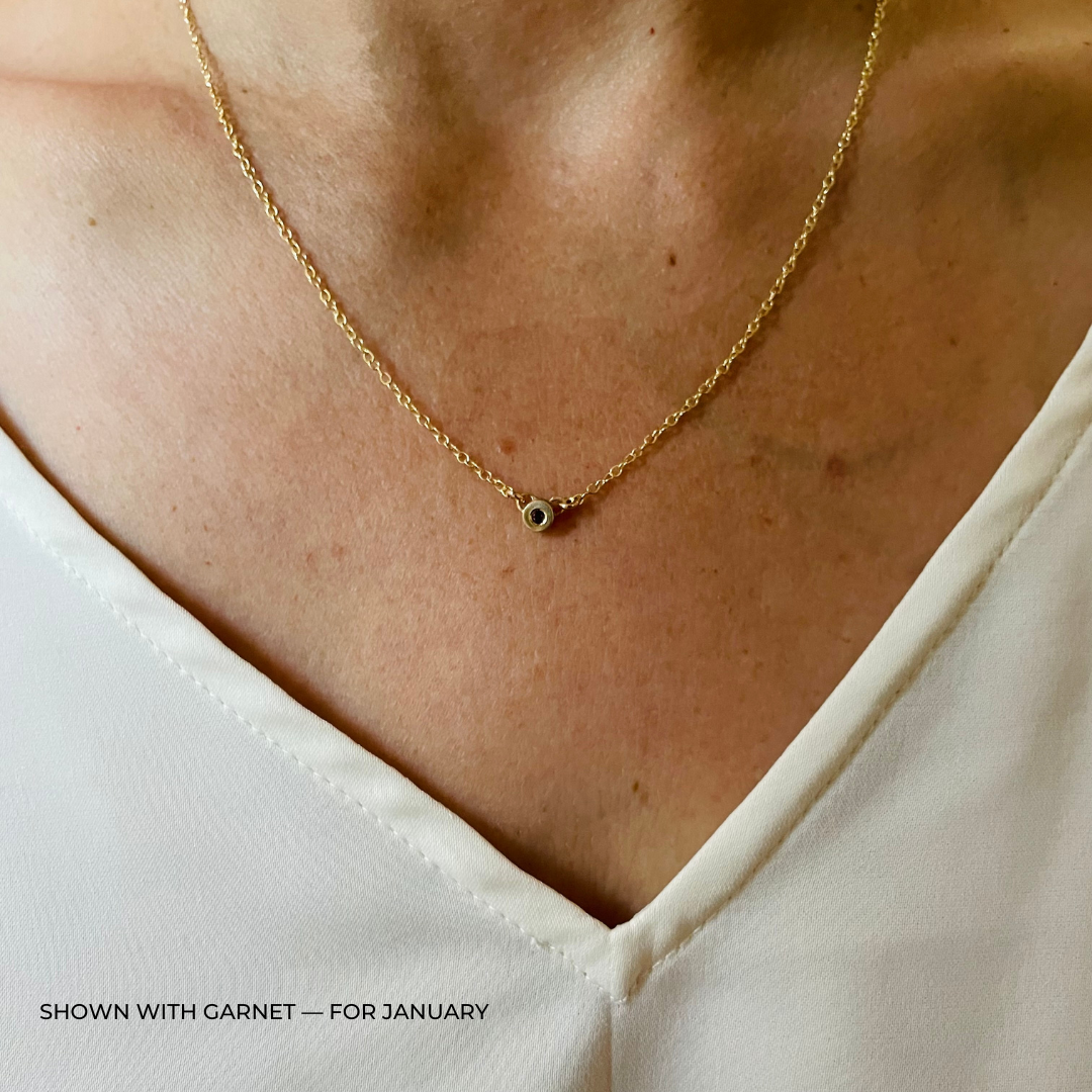 Handmade Bronze Birthstone Necklace with Garnet on Person Wearing a White Top