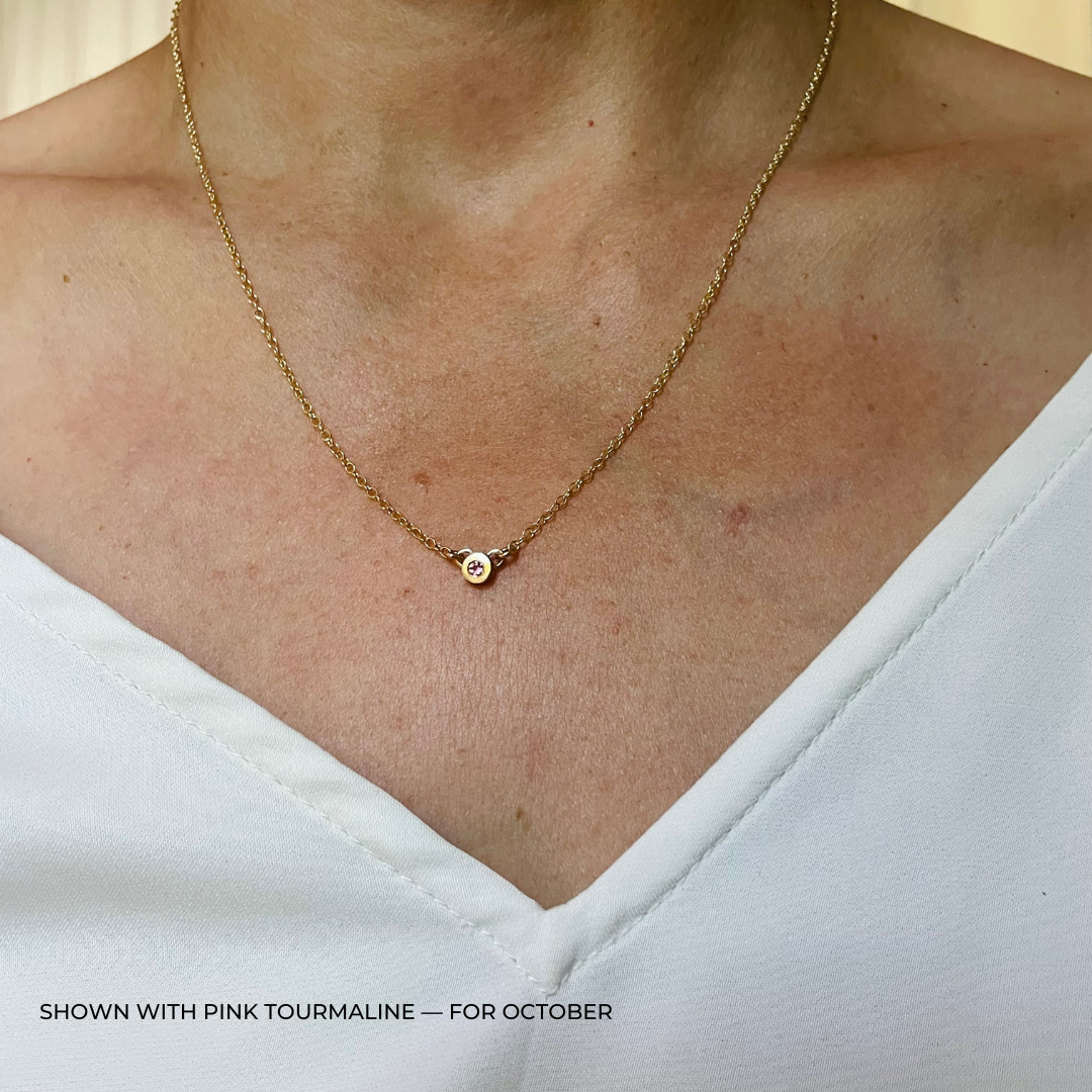 Handmade Bronze Birthstone Necklace with Pink Tourmaline on Person Wearing a White Top