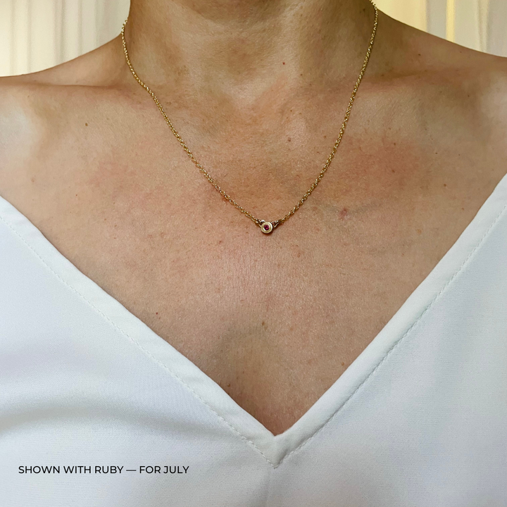 Handmade Bronze Birthstone Necklace with Ruby on Person Wearing a White Top