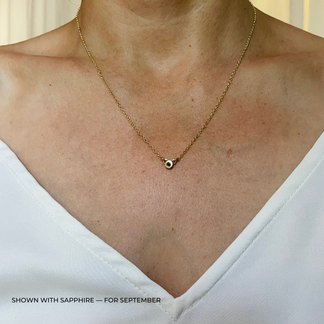 Handmade Bronze Birthstone Necklace with Sapphire on Person Wearing a White Top