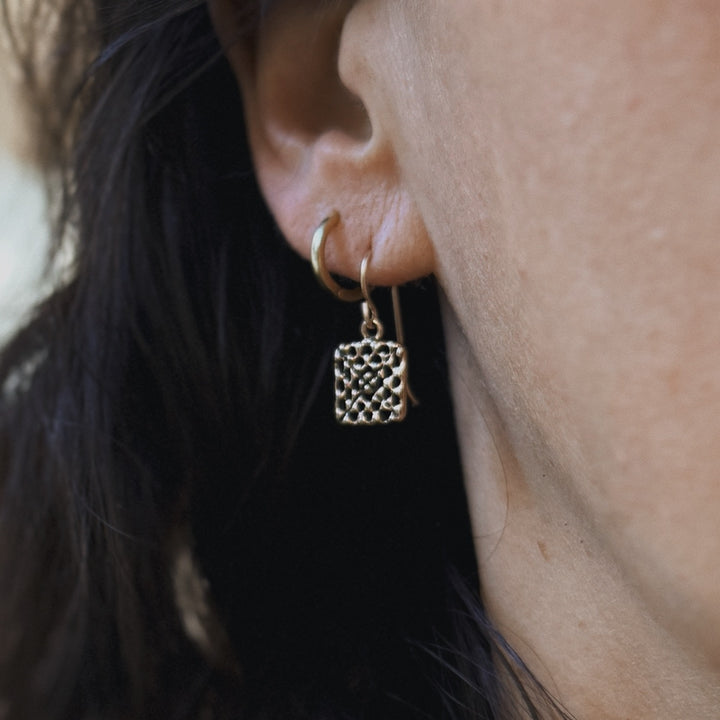 Person wears handmade granny square earrings in bronze by MIMOSA Handcrafted