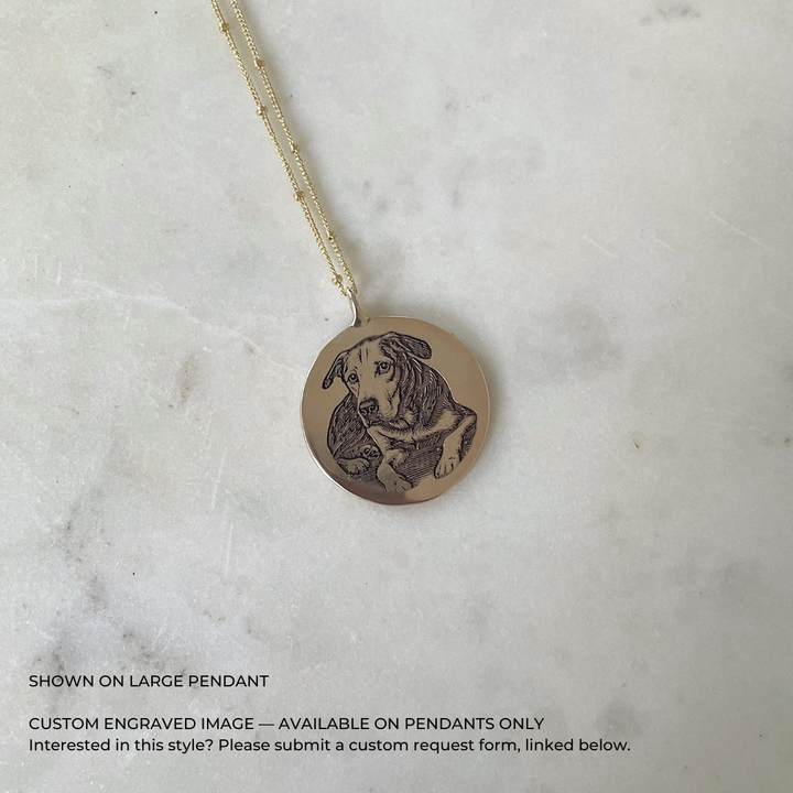 A large, round, bronze pendant necklace featuring a custom engraved portrait of a dog. Available via custom request.