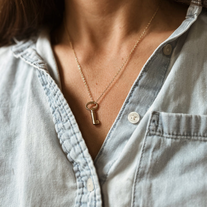 Person Wears the MIMOSA Handcrafted Key Pendant in Bronze