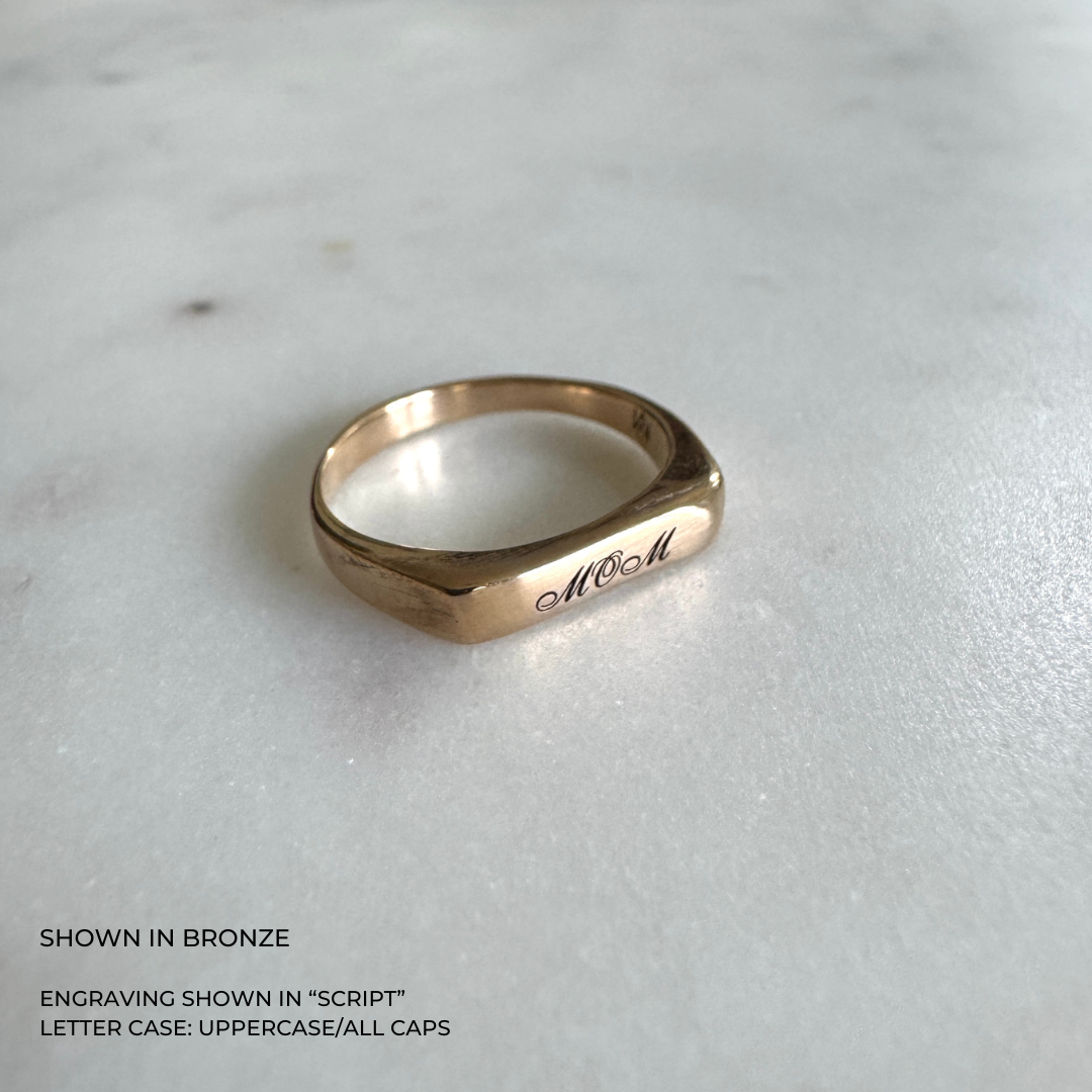 A custom engraved signet ring in a brushed bronze finish, featuring the name &