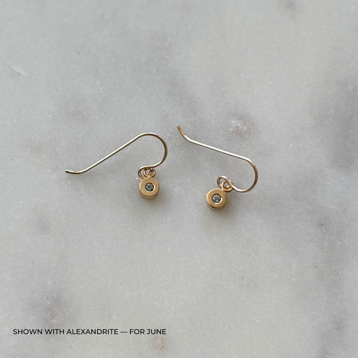 Bronze grace earrings with alexandrite gemstones on a light gray surface