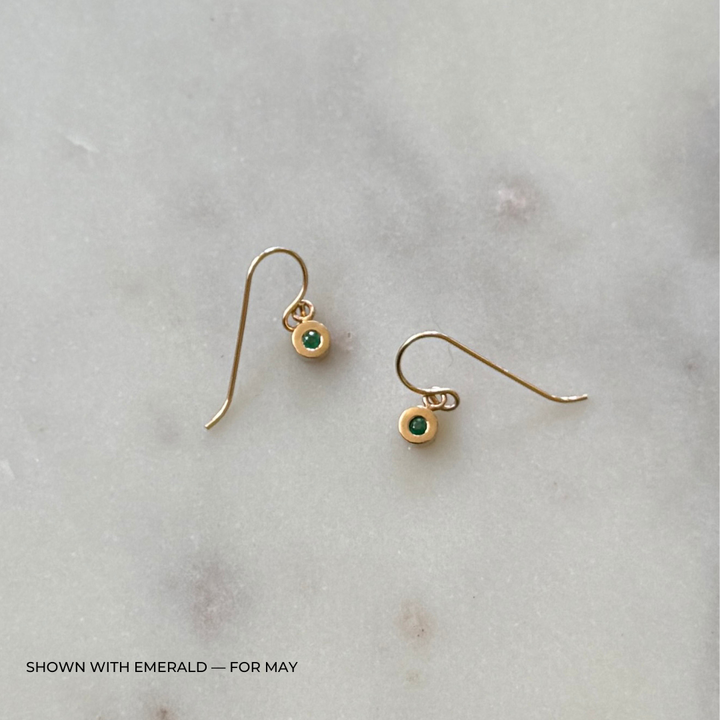 Bronze grace earrings with emerald gemstones on a light gray surface