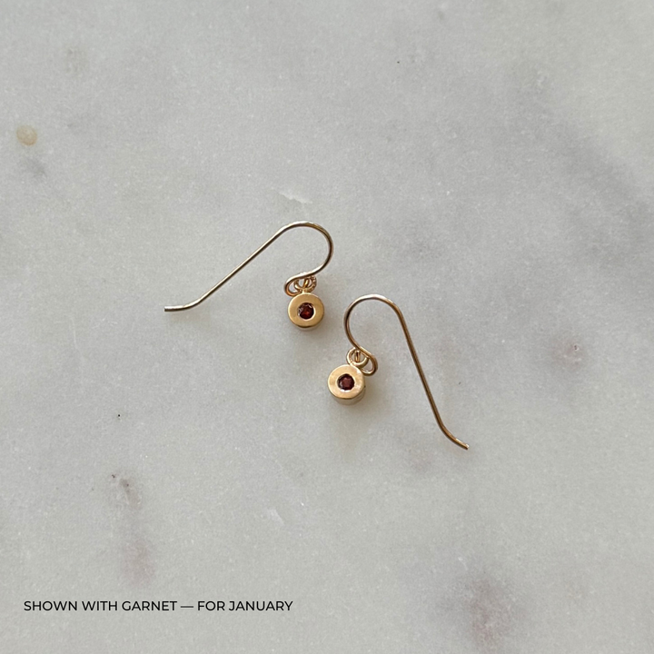Bronze grace earrings with garnet gemstones on a light gray surface