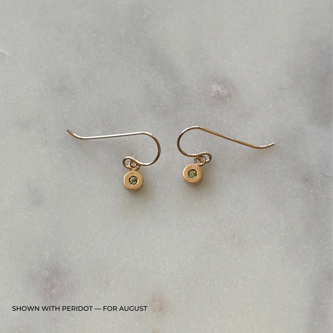 Bronze grace earrings with peridot gemstones on a light gray surface