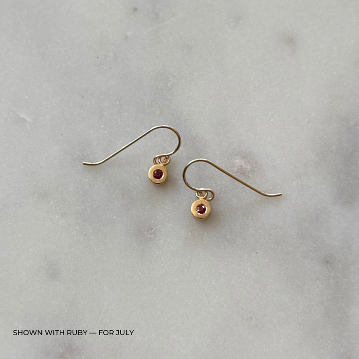 Bronze grace earrings with ruby gemstones on a light gray surface