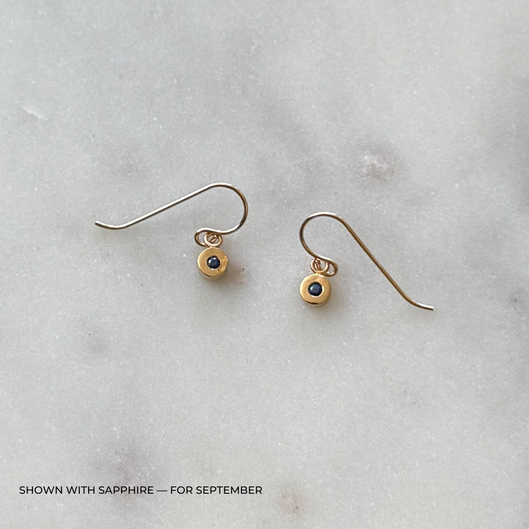 Bronze grace earrings with sapphire gemstones on a light gray surface