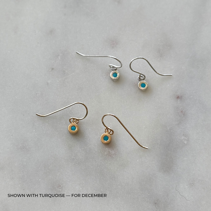 Pair of grace earrings with turquoise stones on a light gray background