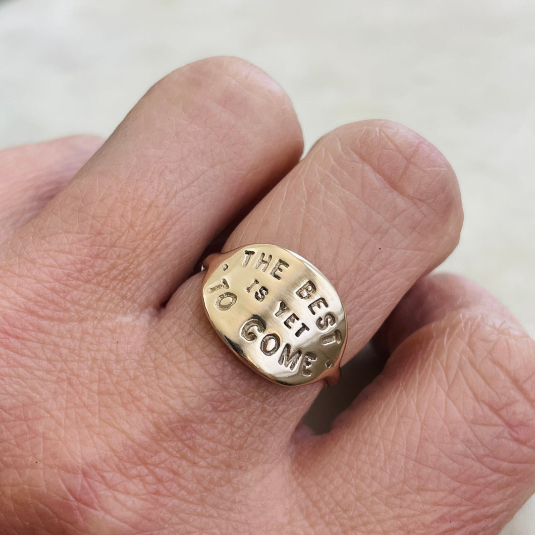 Woman Wearing A Handcrafted 14K Yellow Gold Ring With The Words "The Best Is Yet To Come"