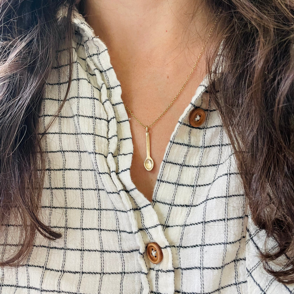 Woman Wears a Bronze Spoon Necklace for MIMOSA's Peanut Butter Drive in Baton Rouge.