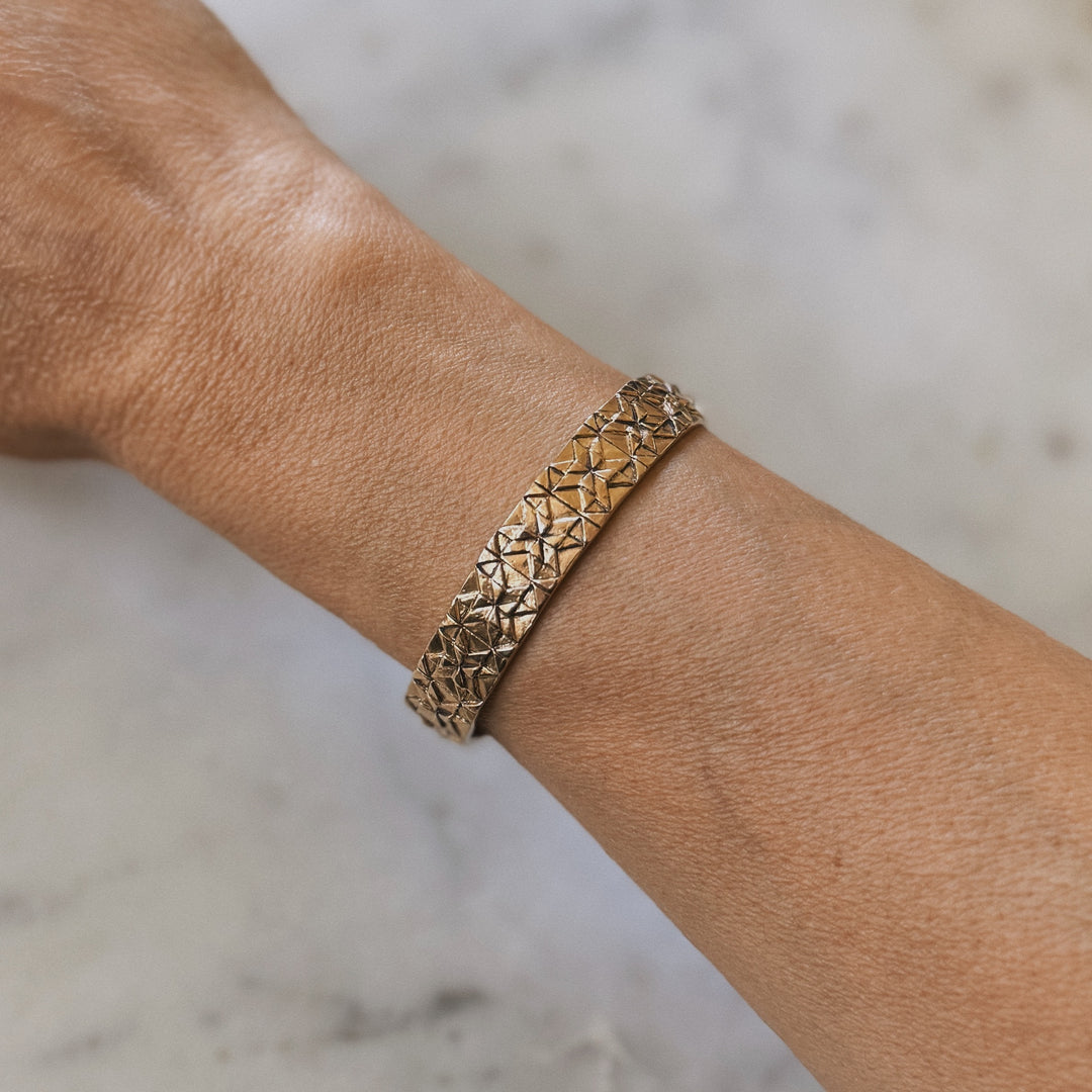 Person wears a handmade quilt square bracelet in bronze by MIMOSA Handcrafted
