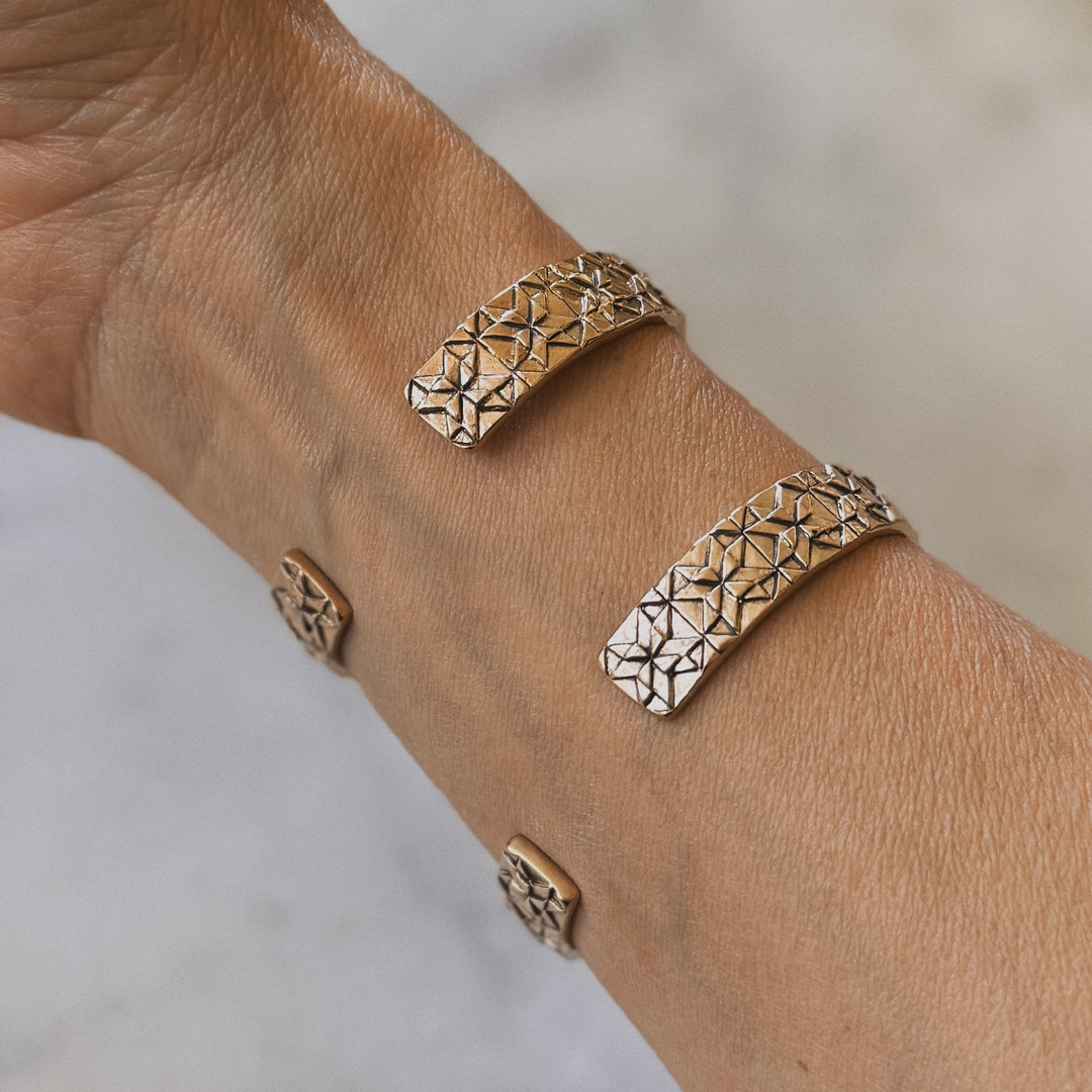 Person wears handmade quilt square bracelets in bronze by MIMOSA Handcrafted