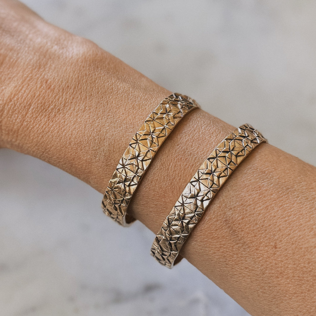 Person wears handmade quilt square bracelets in bronze by MIMOSA Handcrafted