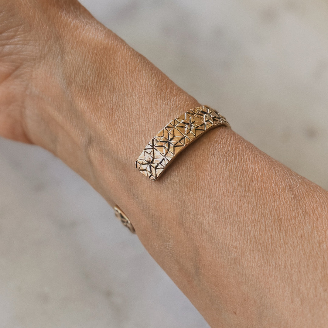 Person wears a handmade quilt square bracelet in bronze by MIMOSA Handcrafted