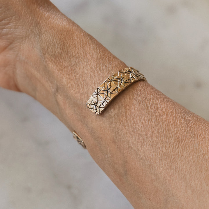 Person wears a handmade quilt square bracelet in bronze by MIMOSA Handcrafted