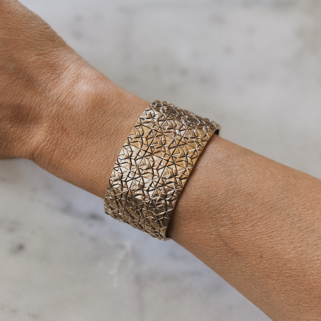 Person wears handmade 3-row quilt bracelet in bronze by MIMOSA Handcrafted