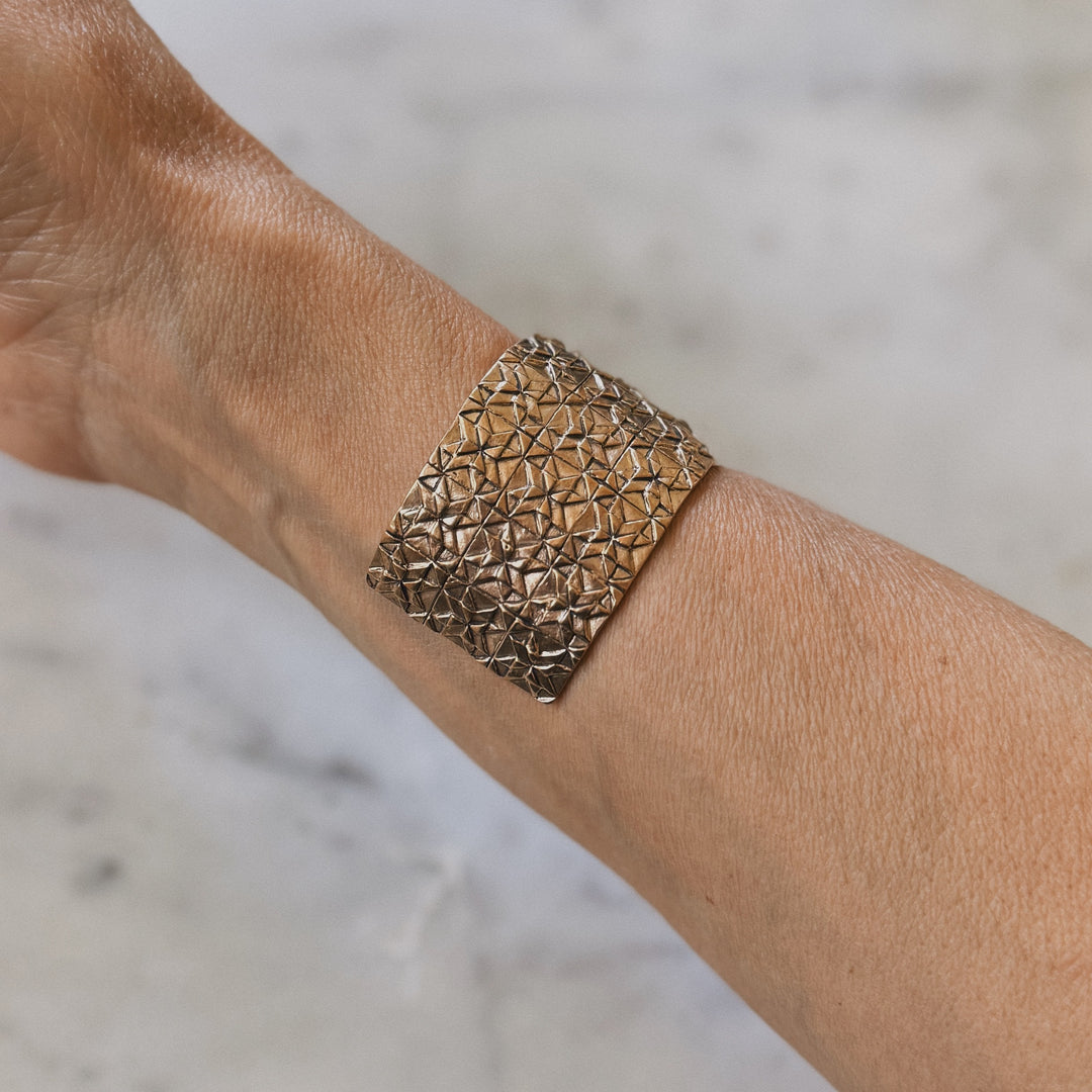 Person wears handmade 3-row quilt bracelet in bronze by MIMOSA Handcrafted