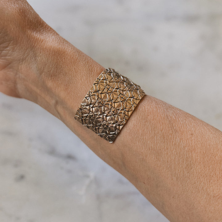 Person wears handmade 3-row quilt bracelet in bronze by MIMOSA Handcrafted
