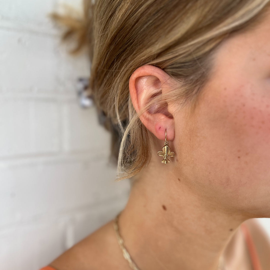 Woman Wears MIMOSA Handcrafted Fleur De Lis Earrings in Bronze.