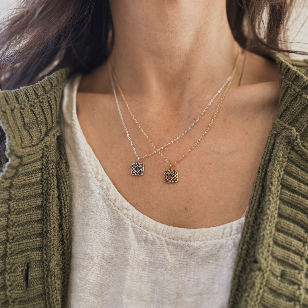 Person wears handmade granny square necklaces in bronze and silver by MIMOSA Handcrafted