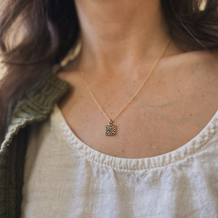Person wears a handmade granny square necklace in bronze by MIMOSA Handcrafted
