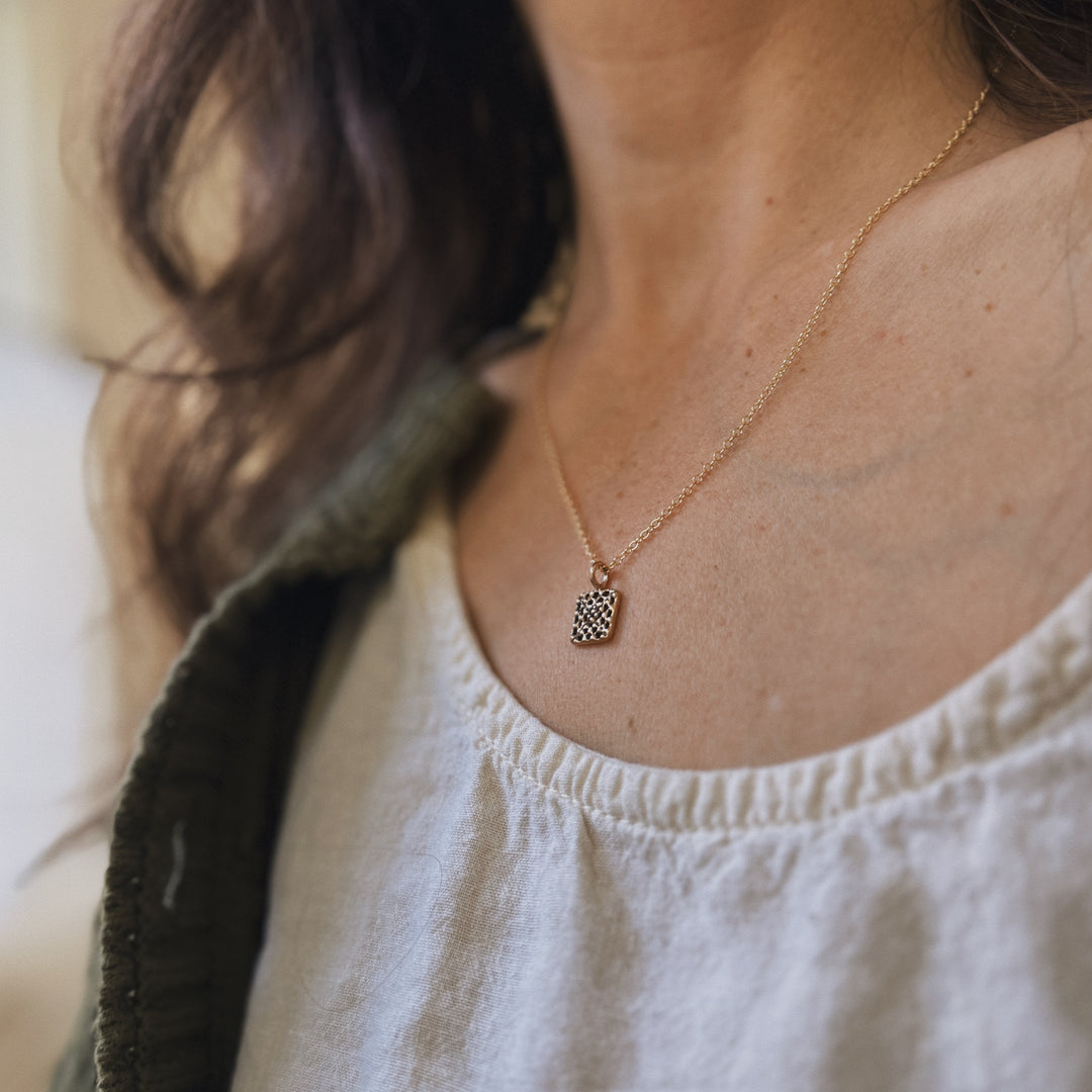Person wears a handmade granny square necklace in bronze by MIMOSA Handcrafted