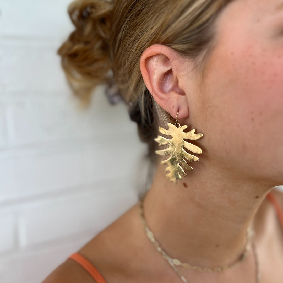 Woman Wears the MIMOSA Handcrafted Philodendron Earrings in Bronze