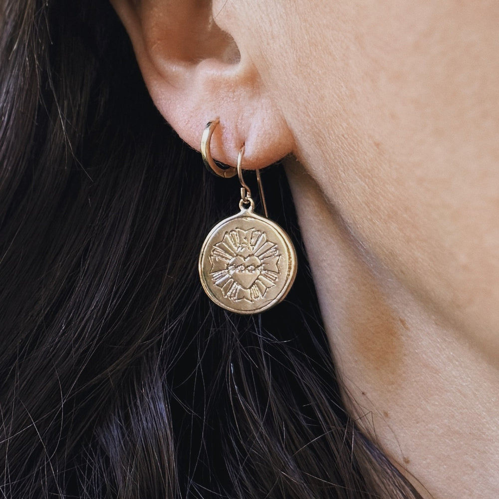 Person wears Bronze Sacred Heart Earrings from MIMOSA Handcrafted