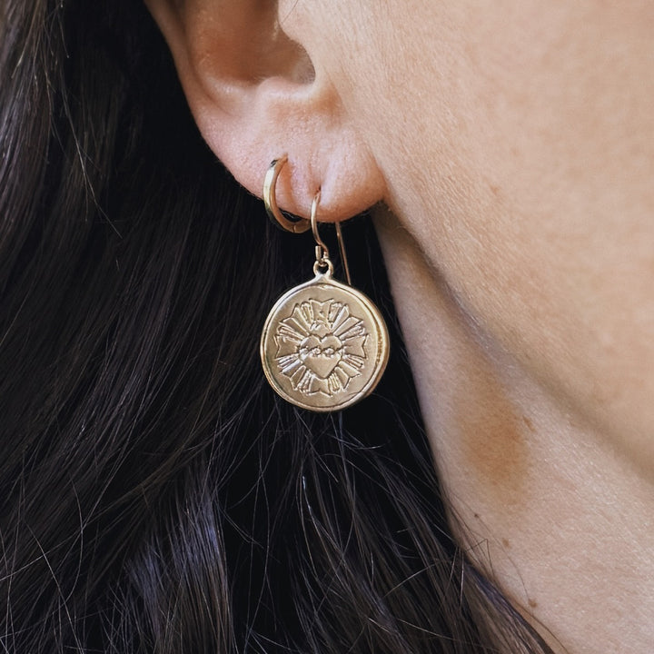 Person wears Bronze Sacred Heart Earrings from MIMOSA Handcrafted