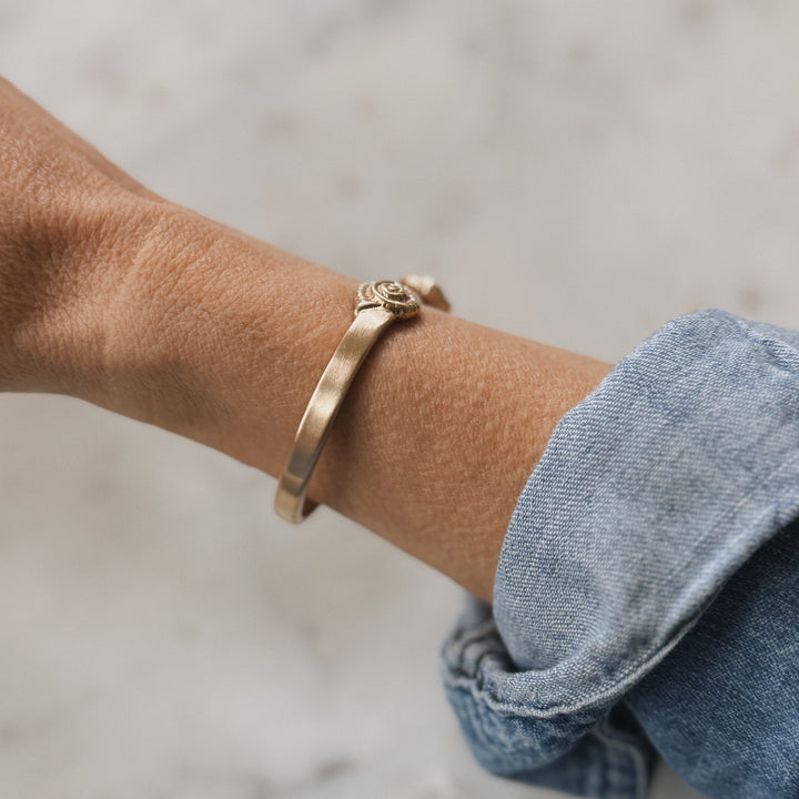 Person Wears Bronze Bracelet with Spiral Snail Shell Design