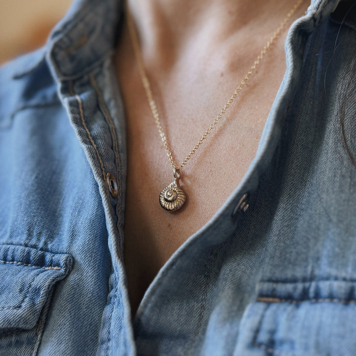 Close UP of a Person Wearing a Bronze Snail Shell Necklace and Denim Shirt