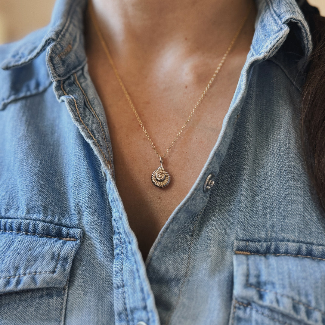 Person Wears a Bronze Snail Shell Necklace and Denim Shirt
