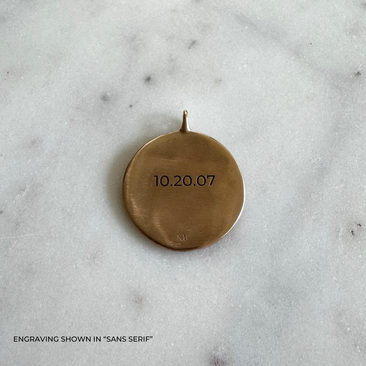 A large round bronze pendant engraved with the date &