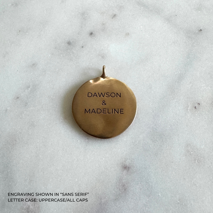 A large round bronze pendant engraved with the names &